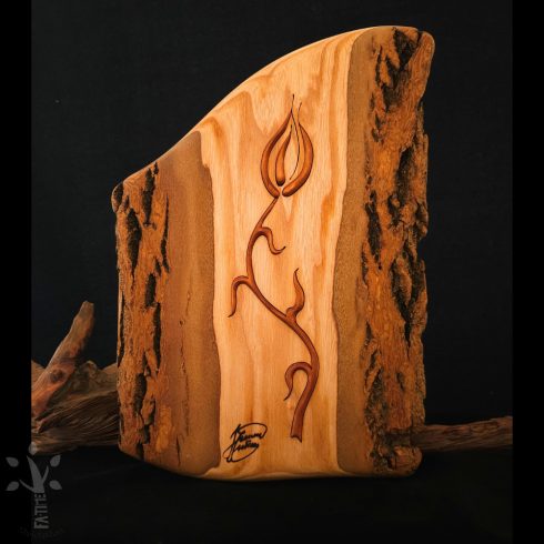 Fából készült fali dekoráció egy kivágott, stilizált tulipánmotívummal. A fa természetes színei harmonizálnak egymással: a világos mézszínű felületet kontrasztos, sötétbarna kérges szélek keretezik. A finoman kidolgozott vonalak mélyebb barna árnyalatokkal emelkedik ki az alapból.